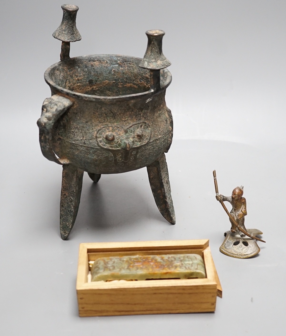 A Chinese green and russet jade belt buckle, an archaistic bronze tripod vessel and a figural bronze. Tallest 25cm